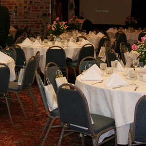 Sala restauracji hotelowej z czerwonym dywanem, stołami przygotowanymi do bankietu oraz tapicerowanymi krzesłami w tkanina obiciowa w kolorze stalowo-szarym.